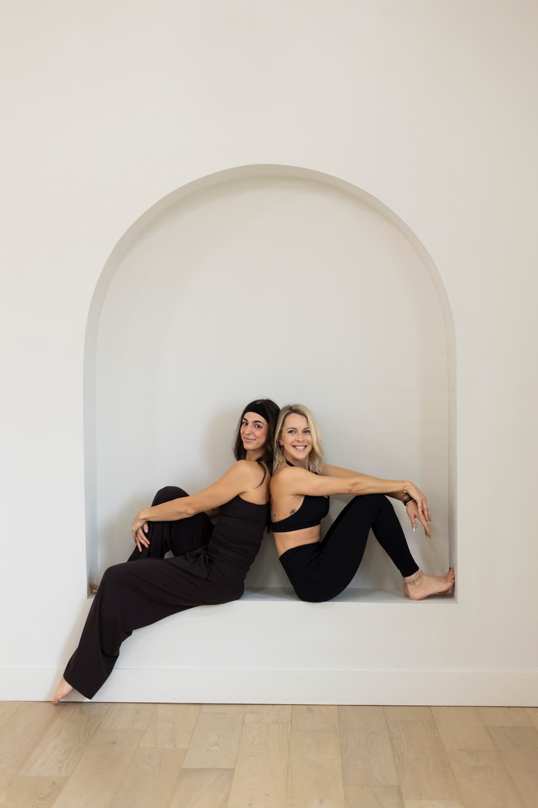Two Refine instructors sitting in the studio's arched alcove